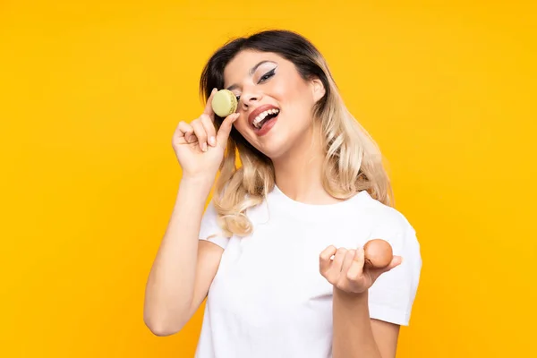 Menina Adolescente Isolada Fundo Amarelo Segurando Macarons Franceses Coloridos — Fotografia de Stock