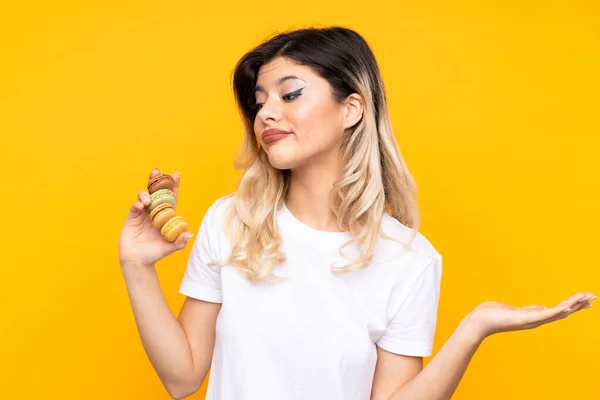 Menina Adolescente Isolada Fundo Amarelo Segurando Macarons Franceses Coloridos Fazendo — Fotografia de Stock