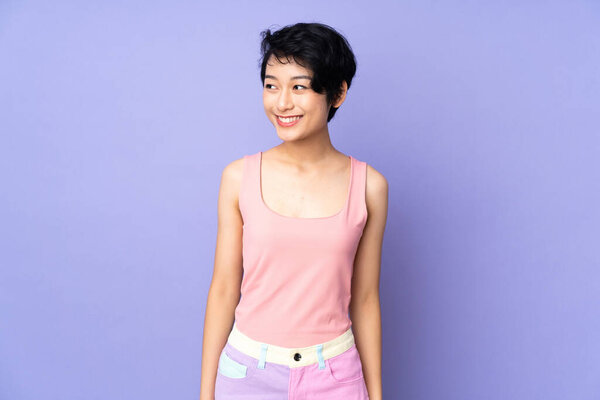Young Vietnamese woman with short hair over isolated purple background looking side