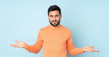 İzole edilmiş mavi arka plan konusunda kuşkuları olan beyaz yakışıklı bir adam.