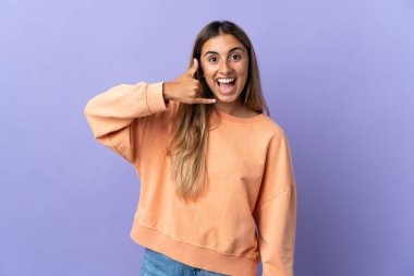 Mor arka planda izole edilmiş İspanyol bir kadın telefon jesti yapıyor. Bana geri dönüş işareti ver.