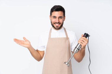 Beyaz arkaplanda izole edilmiş el blenderi kullanan bir adam, el bilgisayarı üzerinde hayali bir kopyalama alanı tutuyor.