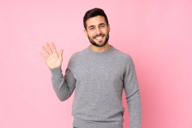 Kafkasyalı yakışıklı adam soyutlanmış arka planda mutlu bir ifadeyle selam veriyor.