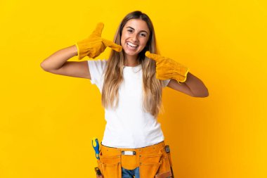 Genç İspanyol elektrikçi kadın izole edilmiş sarı duvarın üzerinde baş parmak hareketi yapıyor.