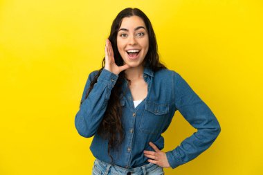 Sarı arka planda izole edilmiş, şaşırmış ve şok olmuş genç bir beyaz kadın.