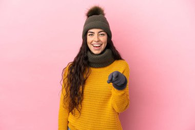 Mor arka planda izole edilmiş beyaz şapkalı genç kız şaşırmış ve ön tarafı işaret ediyor.