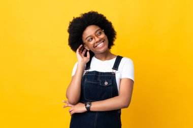 Genç Afrikalı Amerikalı kadın sarı arka planda izole edilmiş bir fikir düşünüyor.