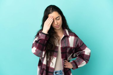 Kafkasyalı genç bir kadın mavi arka planda izole edilmiş, baş ağrısı var.