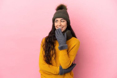 Kışlık şapkalı genç beyaz kız mor arka planda izole edilmiş gülümserken yukarı bakıyor.