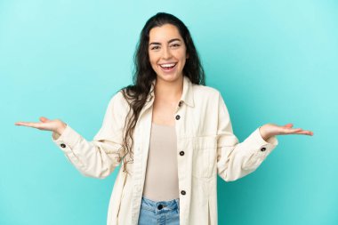 Yüzünde şok ifadesi olan mavi arka planda izole edilmiş beyaz bir kadın.