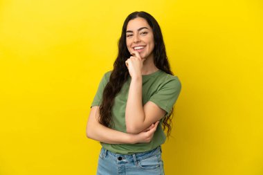 Sarı arka planda izole edilmiş genç beyaz kadın mutlu ve gülümsüyor.