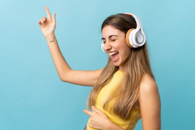 Soyutlanmış mavi arka plan müzik ve dans dinleyen genç bir kadın.