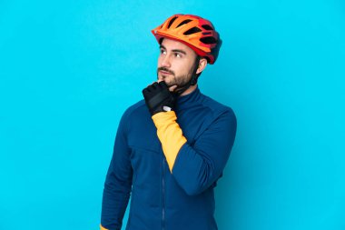 Genç bisikletçi mavi arka planda izole edilmiş ve yukarı bakıyor.