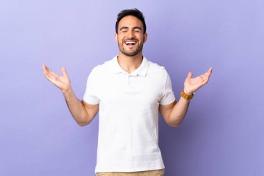 Mor arka planda izole edilmiş genç yakışıklı adam çok gülümsüyor.