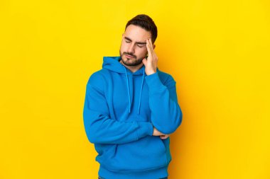 Sarı arka planda yalnız ve başı ağrıyan beyaz, yakışıklı bir genç.