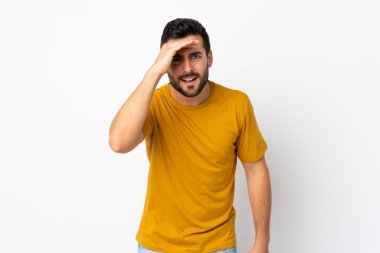 Beyaz arka planda sakallı yakışıklı genç bir adam bir şeye bakmak için uzaklara bakıyor.