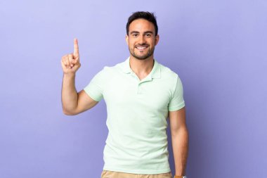 Mor arka planda izole edilmiş genç yakışıklı adam harika bir fikre işaret ediyor.