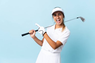 İzole edilmiş mavi duvarın üzerinde genç bir İspanyol golfçü kadın parmak gösterip bir ürün sunuyor.