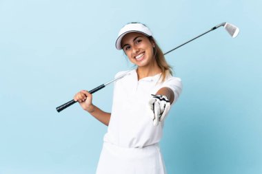 Genç İspanyol golfçü kadın izole edilmiş mavi duvarın üzerinde mutlu bir ifadeyle öne bakıyor.