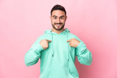 Pembe arka planda yalıtılmış beyaz, yakışıklı, şaşırtıcı bir yüz ifadesi olan genç adam.