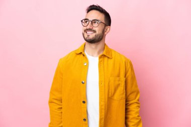 Beyaz tenli yakışıklı bir adam pembe arka planda izole edilmiş, yukarı bakarken bir fikir düşünüyor.