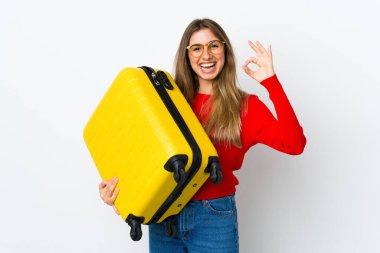 Genç kadın izole edilmiş beyaz arka planda seyahat valiziyle geziyor ve 