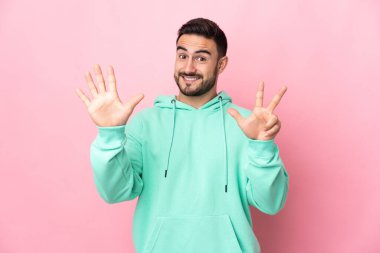 Pembe arka planda izole edilmiş beyaz tenli yakışıklı sekiz parmaklı adam.