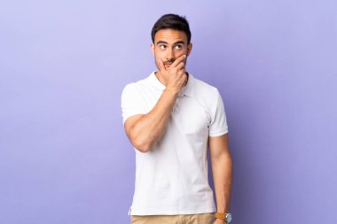 Mor arka planda izole edilmiş genç, yakışıklı bir adam. Şüpheleri var ve kafası karışık.