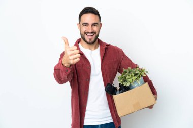 Beyaz arka planda izole edilmiş şeylerle dolu bir kutuyu kaldırırken beyaz bir adam hamle yapıyor çünkü iyi bir şey oldu.