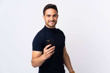 Beyaz arka planda izole edilmiş, mutlu bir ifadeyle cep telefonu kullanan beyaz bir adam.