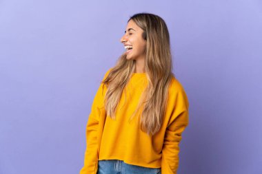 İzole edilmiş mor arka planda genç İspanyol kadın yan yana gülüyor.