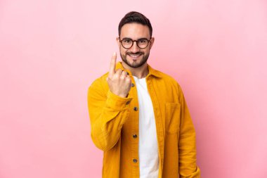 Pembe arka planda izole edilmiş beyaz, yakışıklı genç bir adam geliyor.