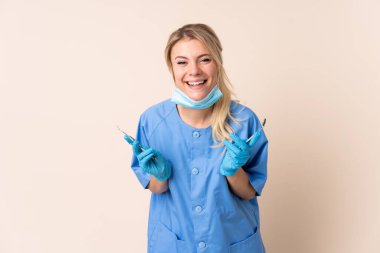 İzole edilmiş arka planda aletleri tutan dişçi kadın