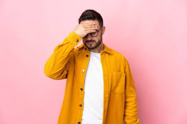 Pembe arka planda yalnız ve başı ağrıyan beyaz, yakışıklı genç bir adam.