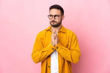 Beyaz tenli yakışıklı bir adam pembe arka planda izole edilmiş bir şeyler çeviriyor.