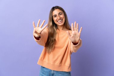 İzole edilmiş mor arka planda genç İspanyol kadın parmaklarıyla dokuz kişi sayıyor.
