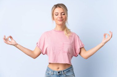 Sarışın kadın, izole edilmiş mavi arka planda zen pozunda.