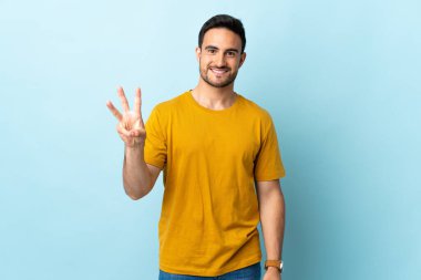 Tecrit edilmiş yakışıklı adam mutlu ve parmaklarıyla üçe kadar sayıyor.