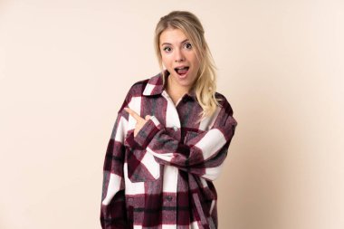 Sarışın kadın izole edilmiş arka planda şaşırmış ve işaret ediyor.