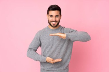 Kafkasyalı yakışıklı, izole edilmiş arka plan üzerinde. Avucunun içinde hayali bir ilan tutuyor.