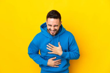 Beyaz tenli yakışıklı adam sarı arka planda izole edilmiş, gülümsüyor.