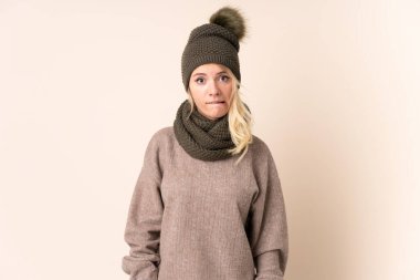Kış şapkalı genç bir kadın izole edilmiş arka planda kuşkuları ve şaşkın bir yüz ifadesi var.