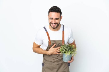 Bahçıvan elinde bir bitki tutuyor. Beyaz arka planda izole edilmiş. Gülümsüyor.