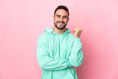 Beyaz tenli yakışıklı adam pembe arka planda izole edilmiş gülüyor.