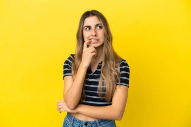 Sarı arka planda izole edilmiş genç beyaz kadın gergin ve korkmuş.