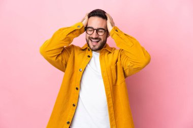 Beyaz tenli yakışıklı adam pembe arka planda izole edilmiş gülüyor.