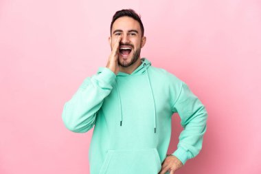 Pembe arka planda izole edilmiş, ağzı açık, bağıran beyaz, yakışıklı bir genç.