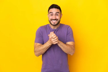 Sarı arka planda izole edilmiş genç beyaz yakışıklı adam gülüyor.