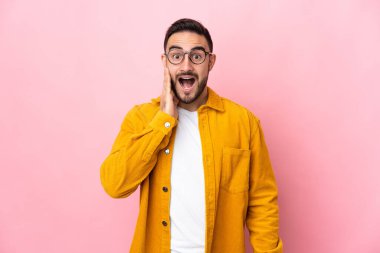 Pembe arka planda mahsur kalmış beyaz, yakışıklı bir genç. Şaşırmış ve şok olmuş bir yüz ifadesi var.