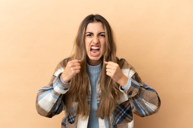 Beyazlı genç bir kadın bej arka planda izole edilmiş. Kötü bir durum yüzünden hayal kırıklığına uğramış.